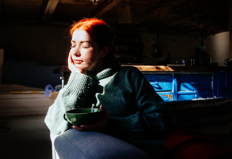 Portrait of woman drinking tea in sunlight.