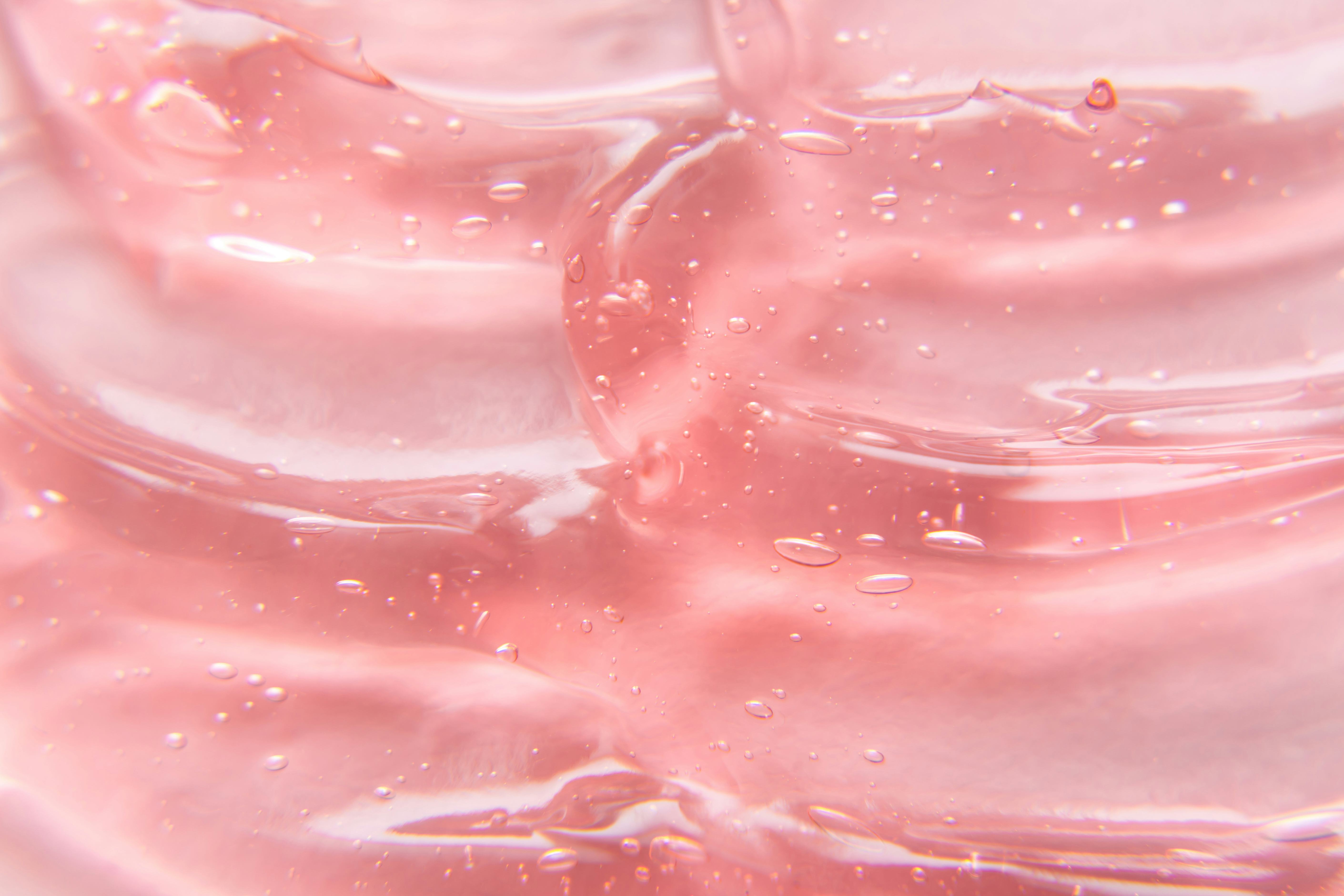 Texture of gel cream. Liquid hyaluronic acid gel on pink background.