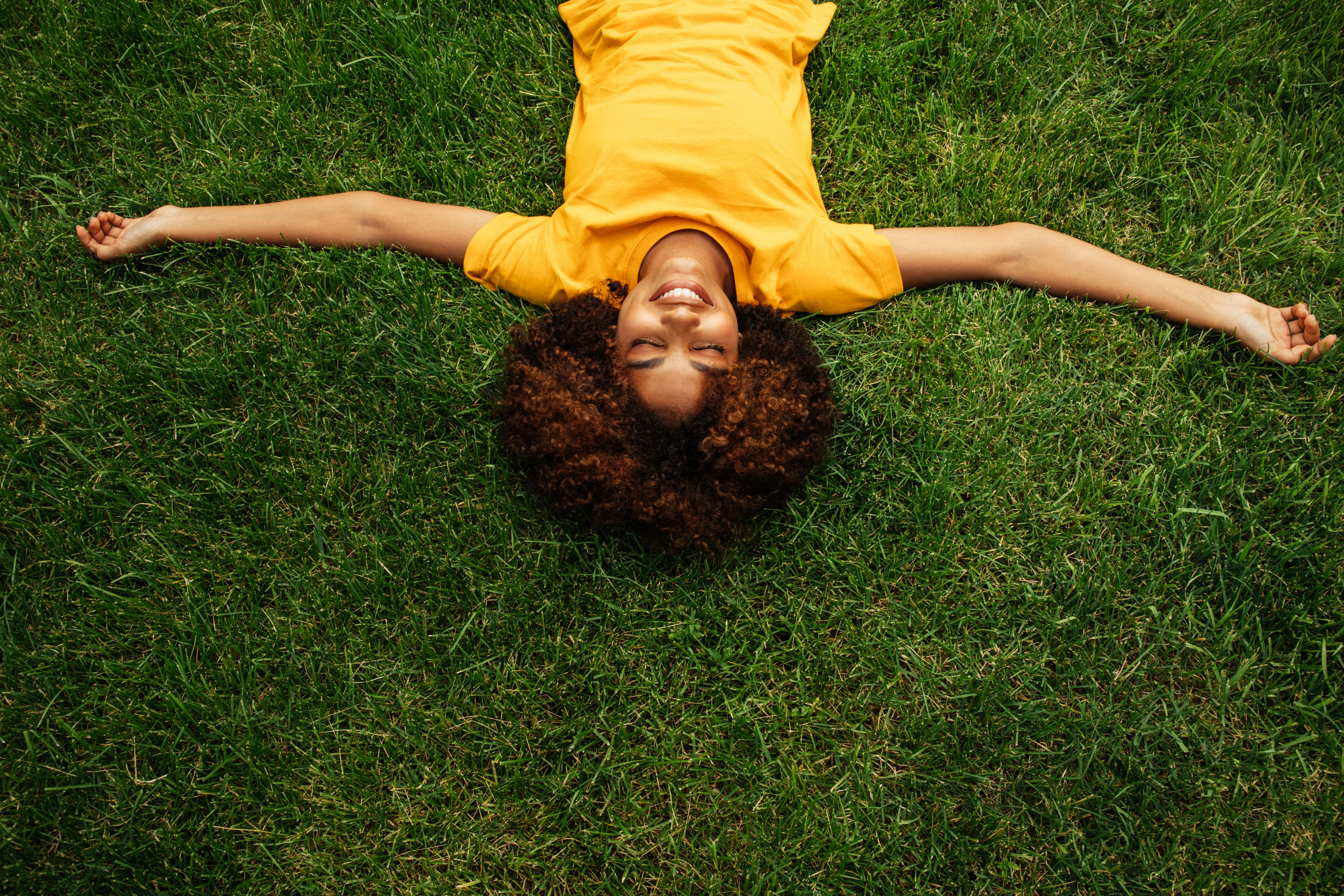 A woman lies in the grass. cancer season 2022 do's and don'ts.