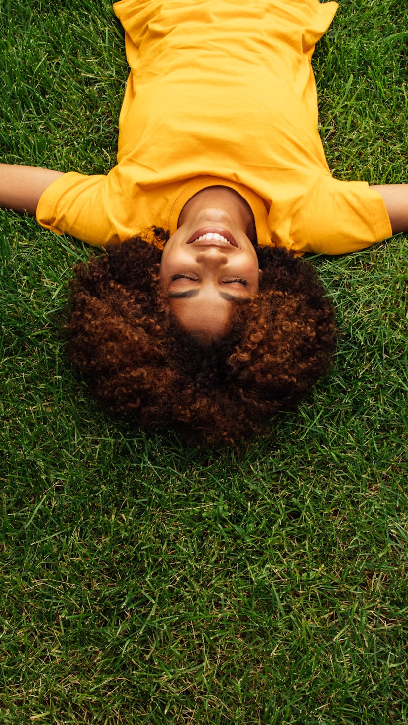 A woman lies in the grass. cancer season 2022 do's and don'ts.