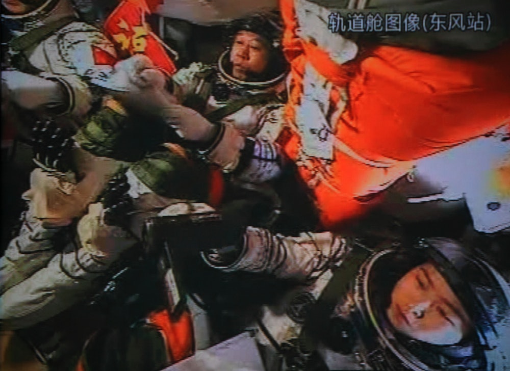 A photo of the giant screen at the Jiuquan space center shows three Chinese astronauts (from left) L...