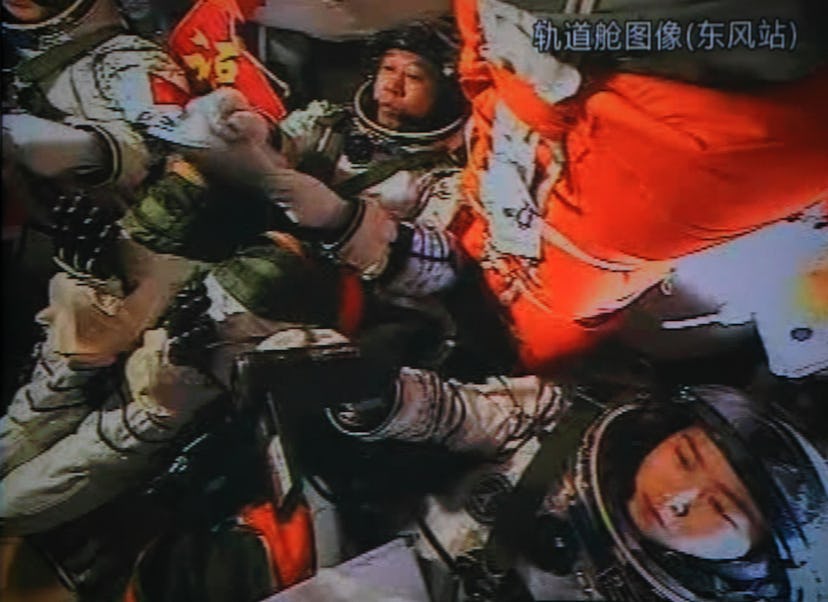 A photo of the giant screen at the Jiuquan space center shows three Chinese astronauts (from left) L...
