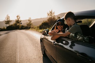 Mother and her young son riding in a car on urban road, they are going on a road trip.