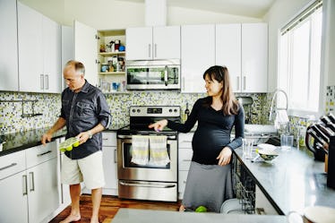 一对怀孕的夫妇一起在家里厨房卸载洗碗机