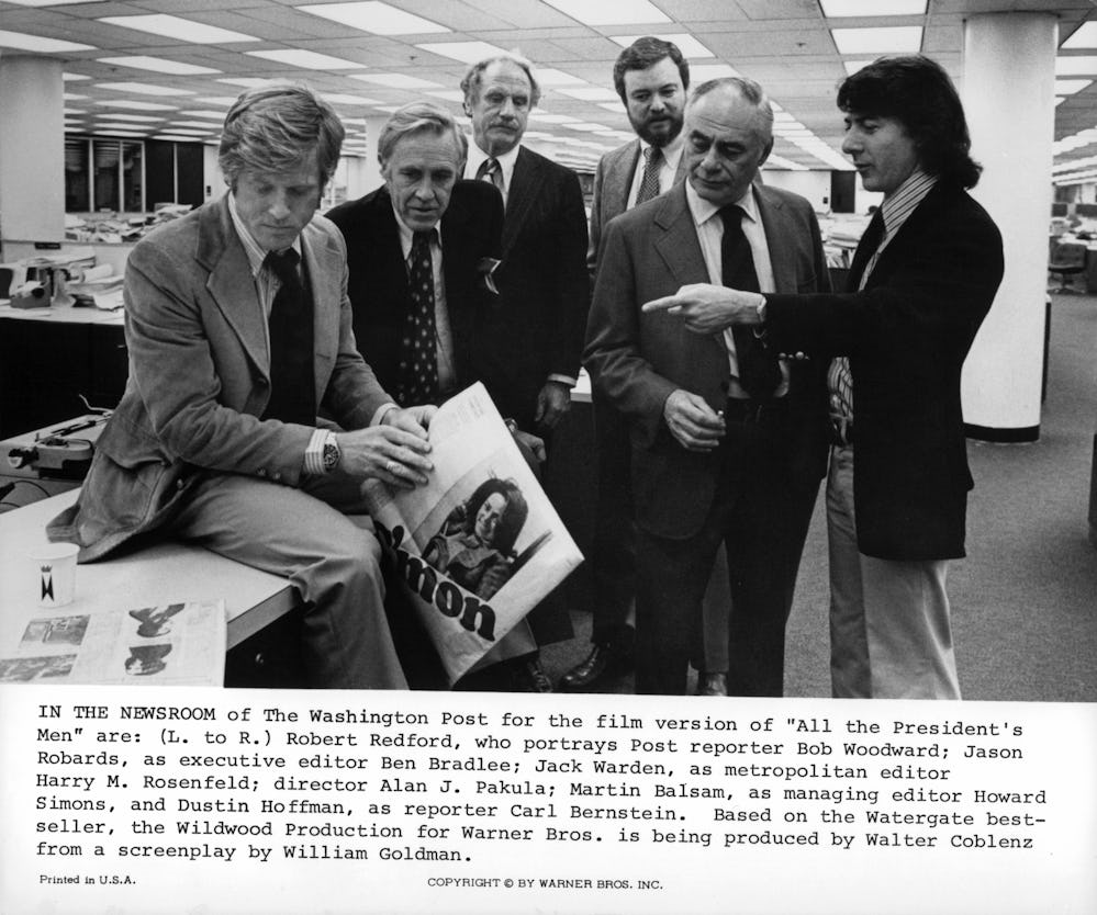 Robert Redford sitting on a desk with Dustin Hoffman pointing at him in a scene from the film 'All T...