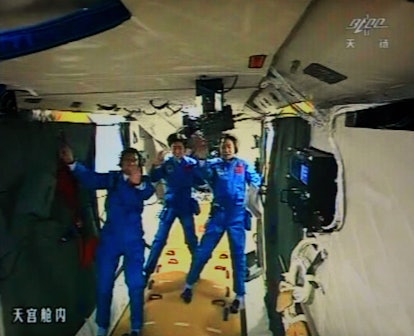 A photo of the giant screen at the Jiuquan space center shows three Chinese astronauts (from left) L...