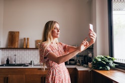 Blonde Caucasian woman taking a selfie using her smartphone. TikTok is testing a new clear mode for ...