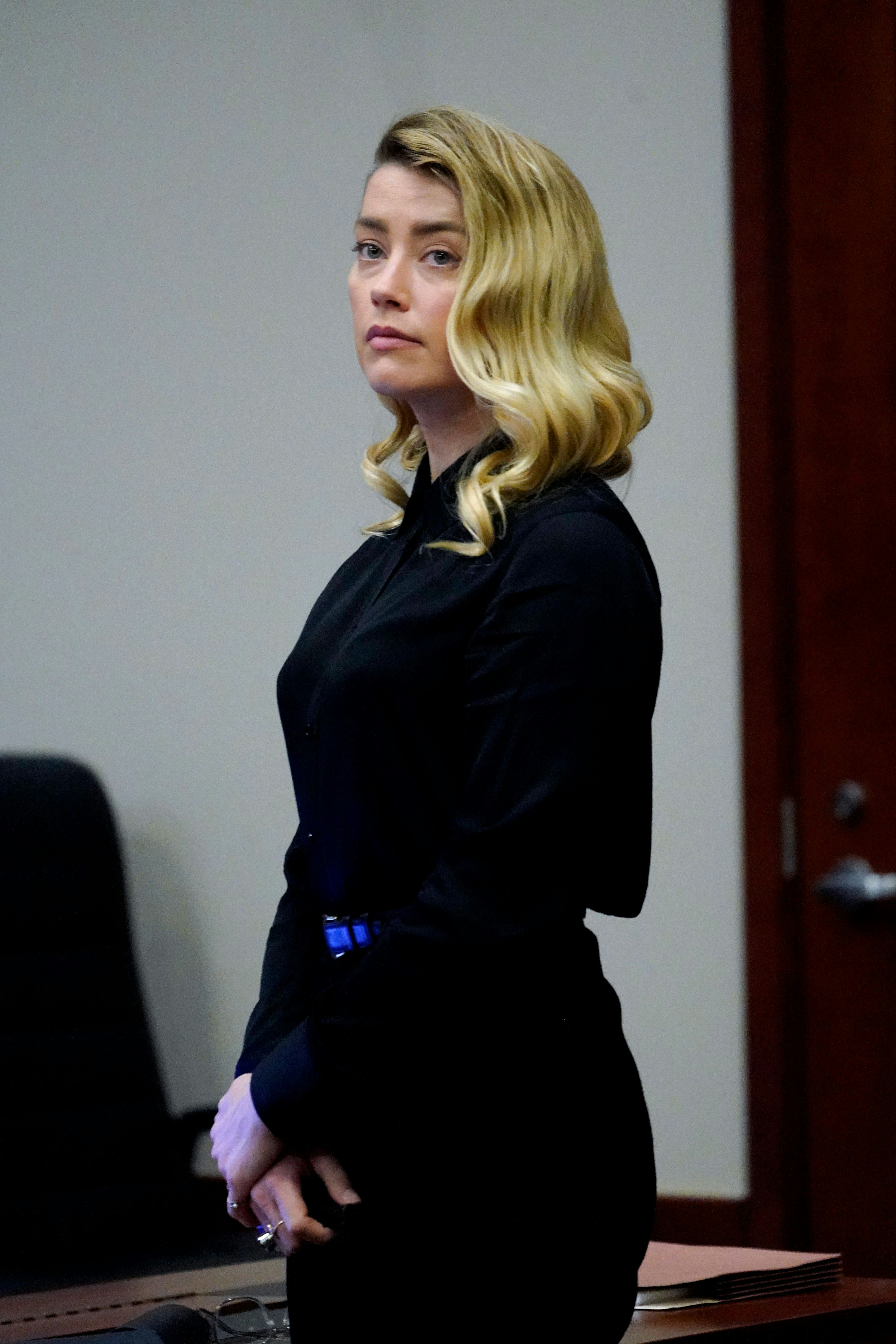 US actress Amber Heard stands and watches the jury leave as a lunch break starts at the Fairfax Coun...