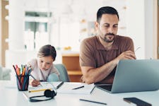 Man working on a laptop and a little girl drawing next to him