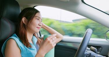 close up of relaxed asian woman experiences riding autonomous self driving car and drinking on highw...