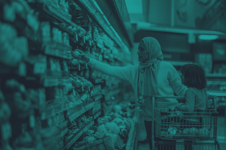 A young Muslim mother and daughter walk the produce aisles of the grocery store together shopping fo...