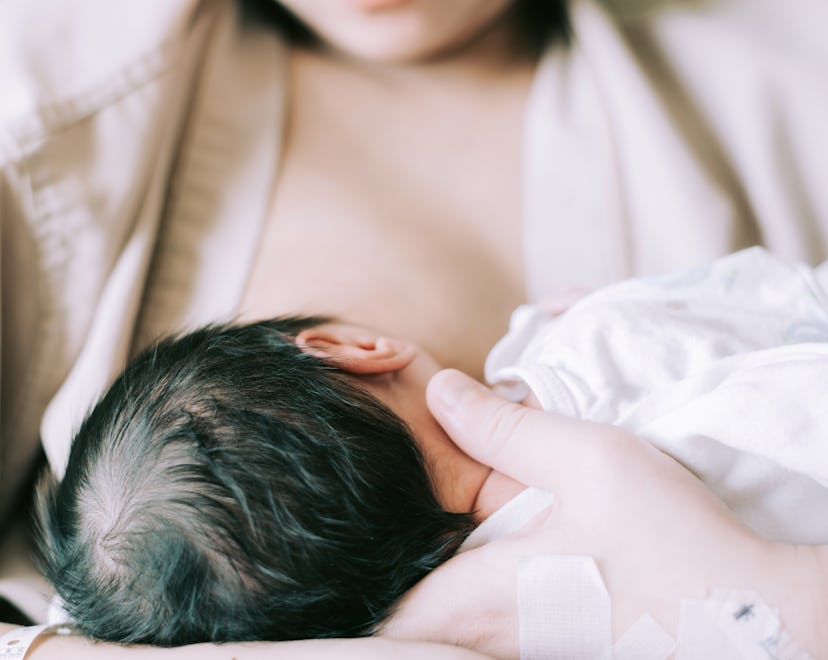 mother nursing a newborn baby in article about colostrum harvesting