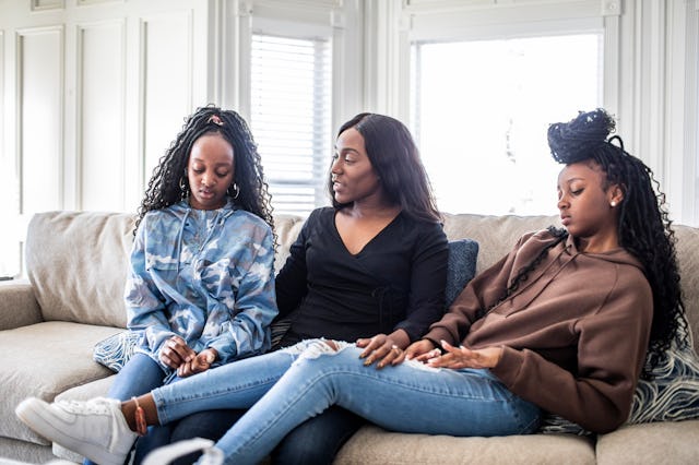 Mother talking with teenage daughters on sofa