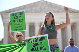 Pro-choice activists with signs that say, "Overturn Roe? Hell No!" States like Minnesota and Illinoi...