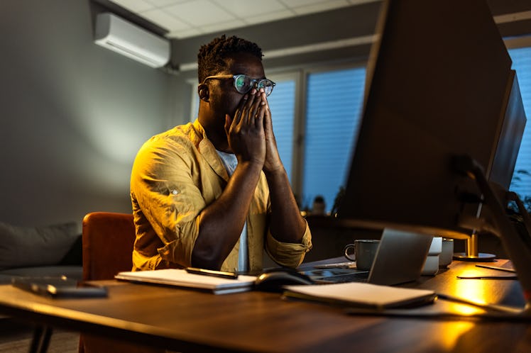 Sleepy exhausted freelancer working on computer at home
