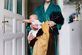 A single mother with her baby trying to get dressed in the morning, carrying clothes to get changed.
