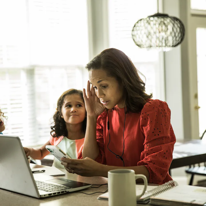 Mother working from home with children in background. A new study from Ohio State reports that 66% o...