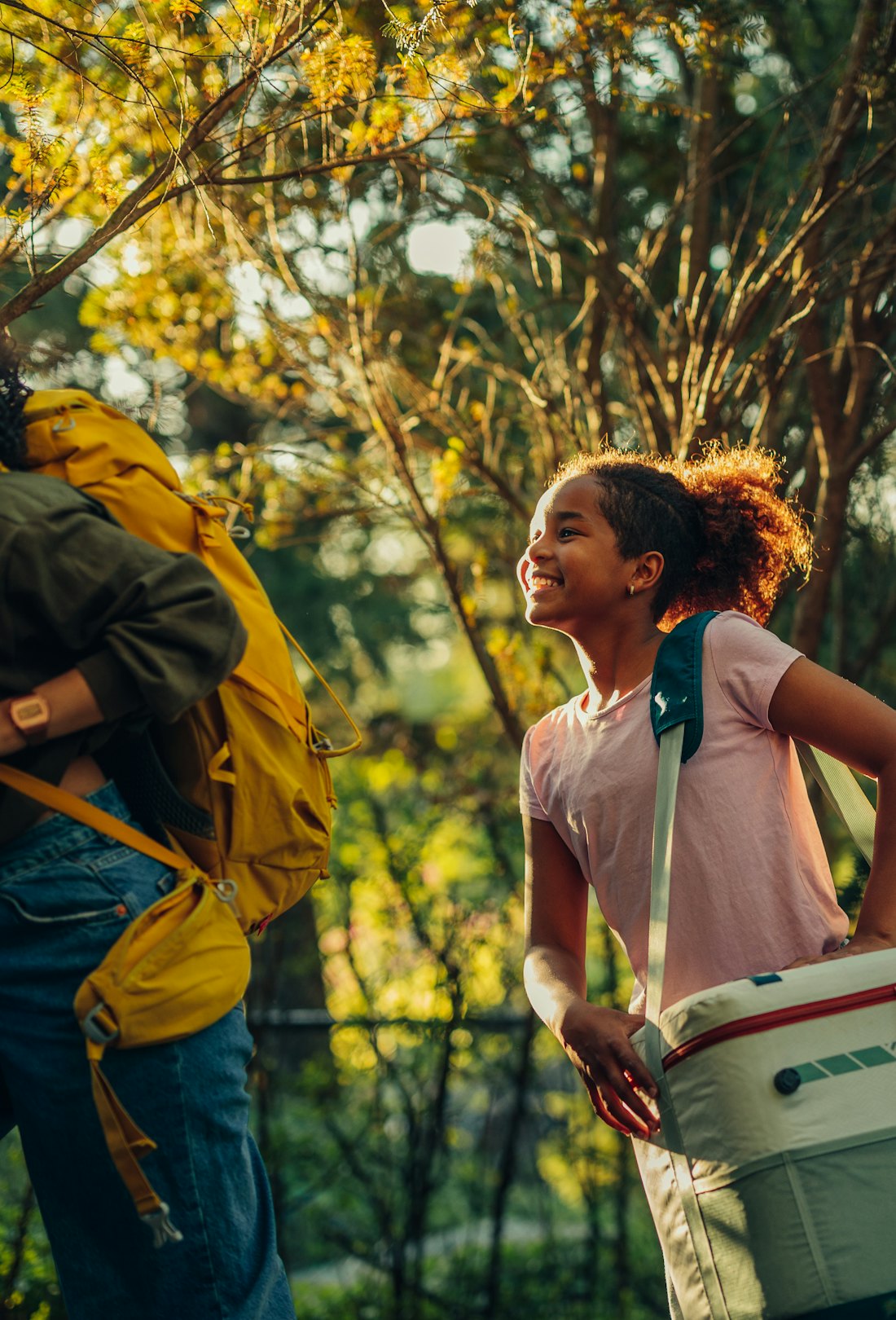 Parents and their daughter carrying gear to their campsite while camping with kids.