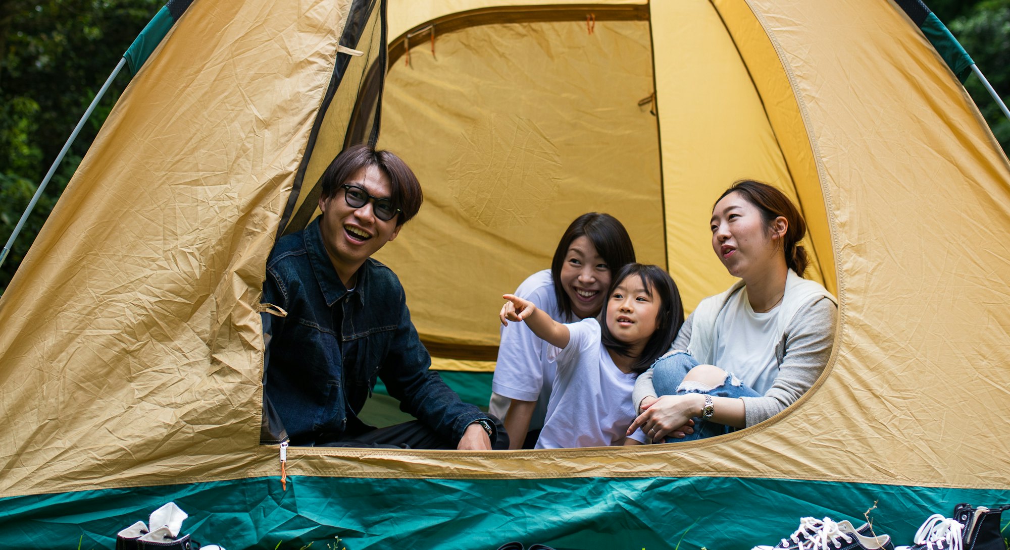 A family camping with kids together in a tent in the forest.