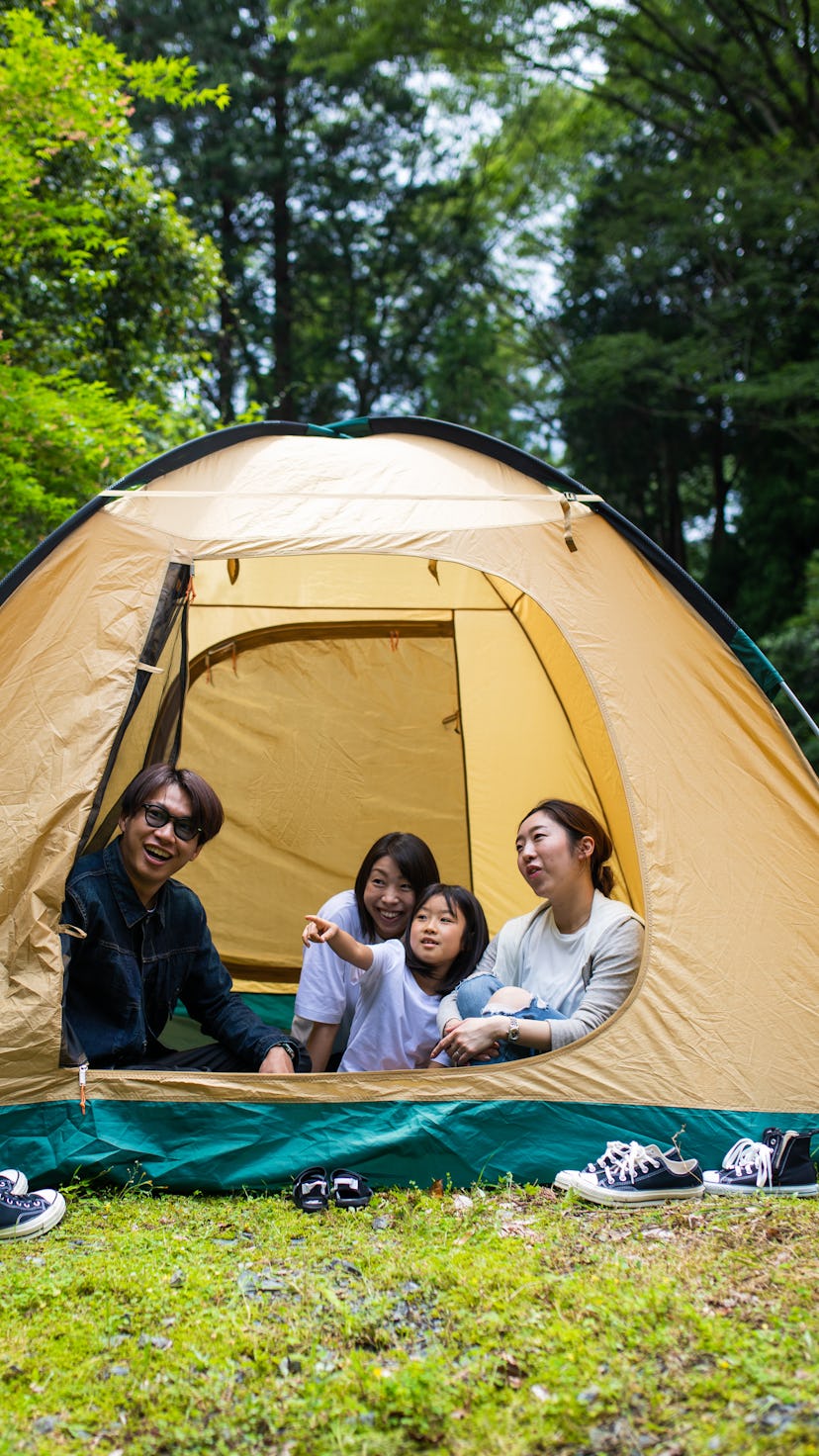 A family camping with kids together in a tent in the forest.