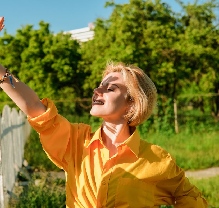 Young woman smiles as she shuts her eyes blocks the sun from her face as she thinks about the June 2...