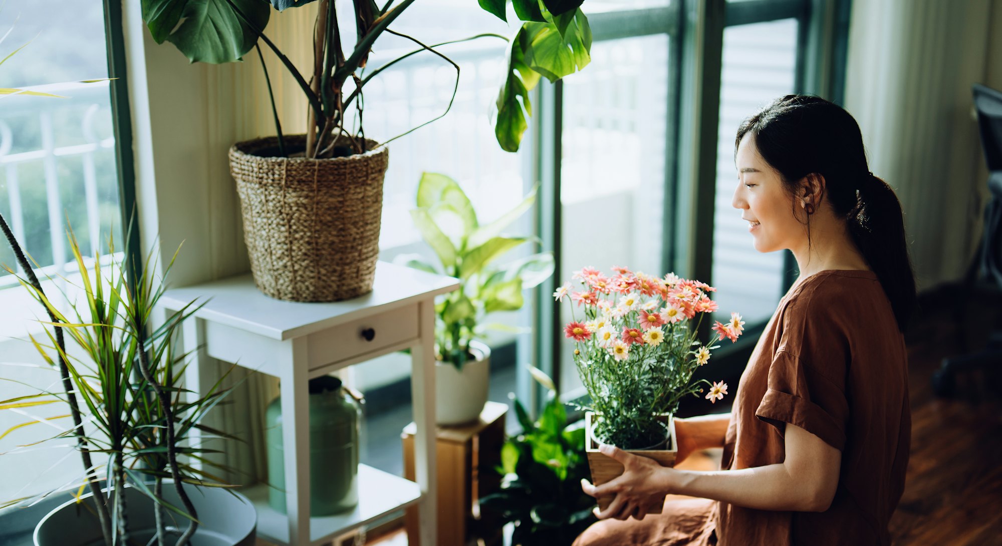 woman taking care of her plants by the window. June 2022 new moon do's and don'ts.