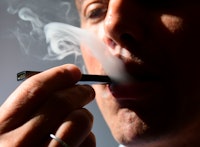 An illustration shows a man exhaling smoke from an electronic cigarette in Washington, DC on October...