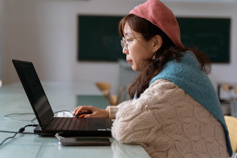 A close-up of a woman using a computer. During Saturn retrograde, focus on achieving your goals.
