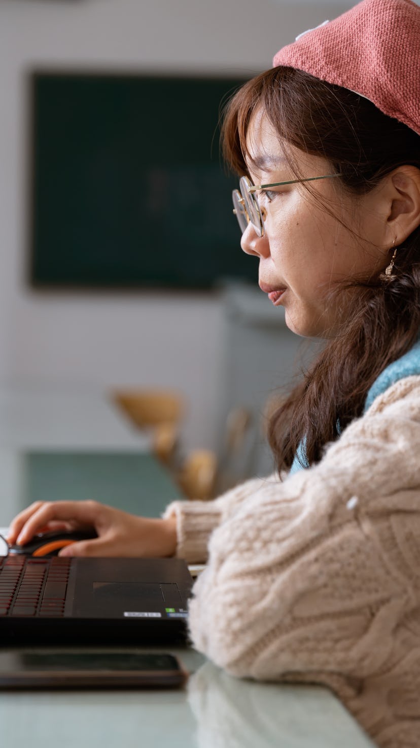 A close-up of a woman using a computer. During Saturn retrograde, focus on achieving your goals.