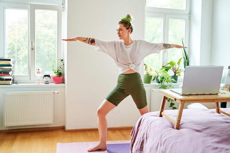 A woman does warrior II as a summer solstice yoga sequence.