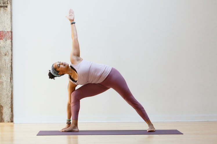 A woman does triangle pose as a summer solstice yoga sequence.