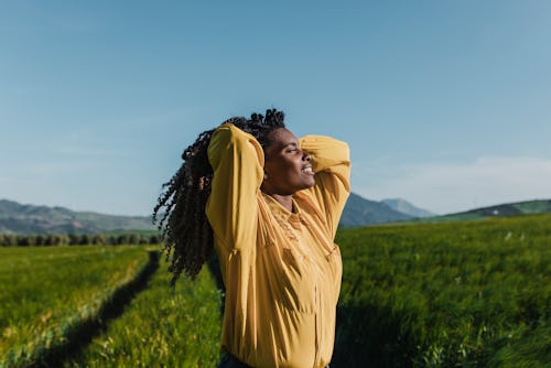 A woman lifts her hair up while walking in a field. The June 2022 New Moon Will Affect These Zodiac ...