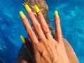 A woman shows off neon coffin nails with 3d nail art, two of summer 2022's nail trends 