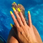 A woman shows off neon coffin nails with 3d nail art, two of summer 2022's nail trends 