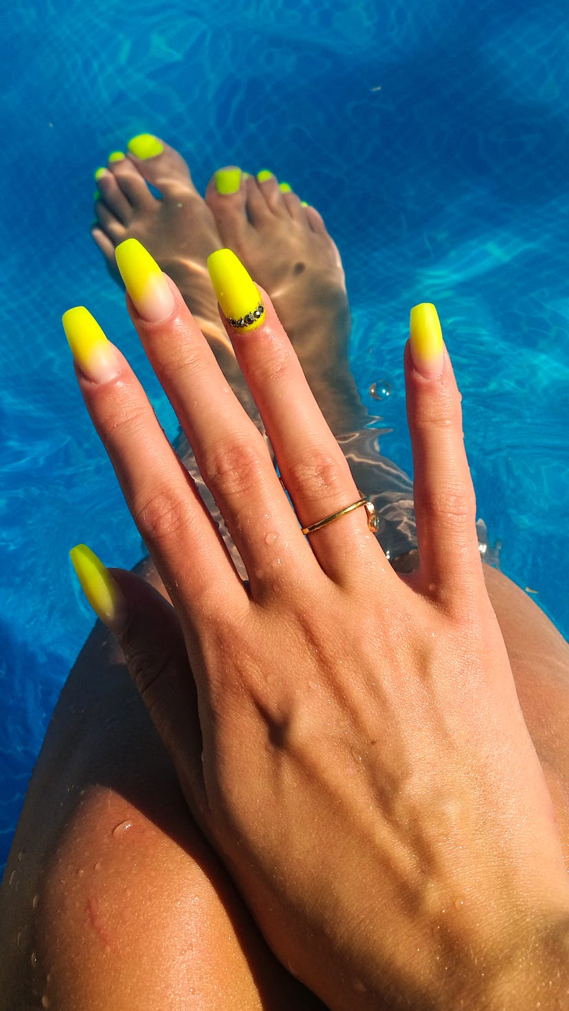 A woman shows off neon coffin nails with 3d nail art, two of summer 2022's nail trends