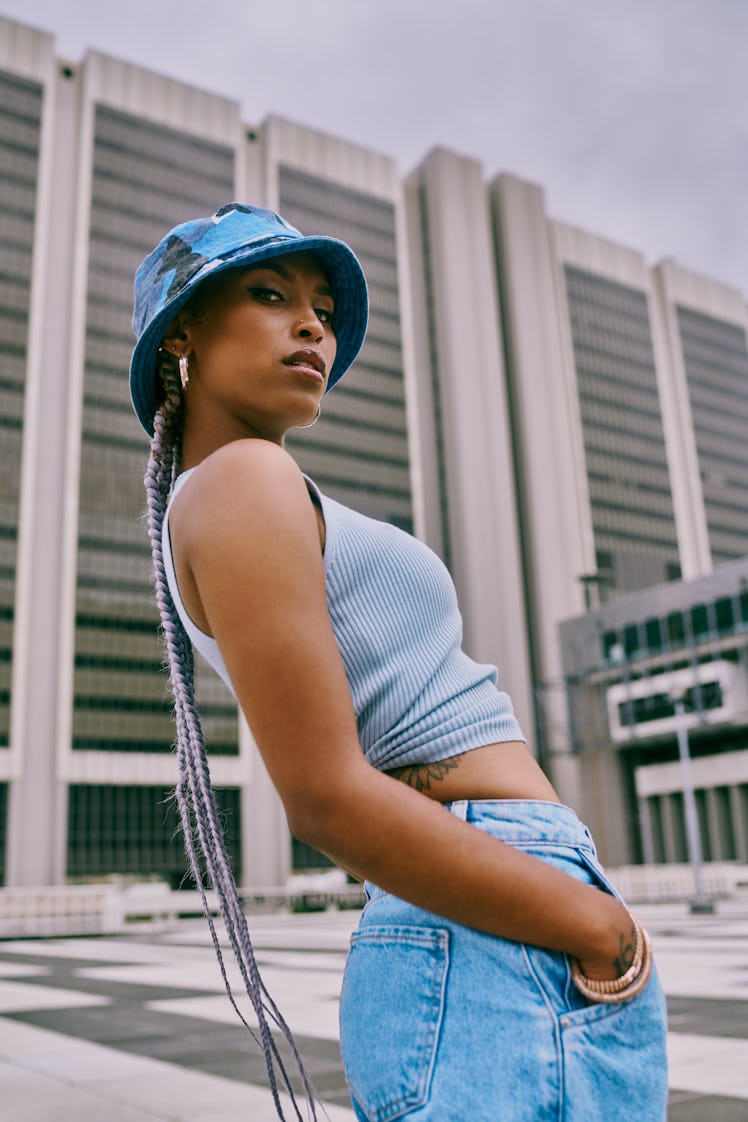 Young woman wearing bucket hat leans back as she thinks about the new moon in cancer on June 28, 202...