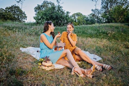 Two women enjoy a picnic at dusk. Here's the spiritual meaning of the june 2022 new moon.