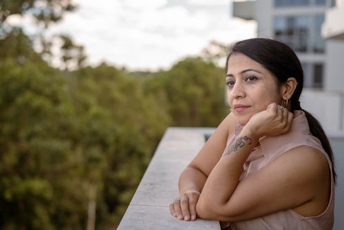 A woman looks out over a balcony. Here’s your june 24 zodiac sign daily horoscope