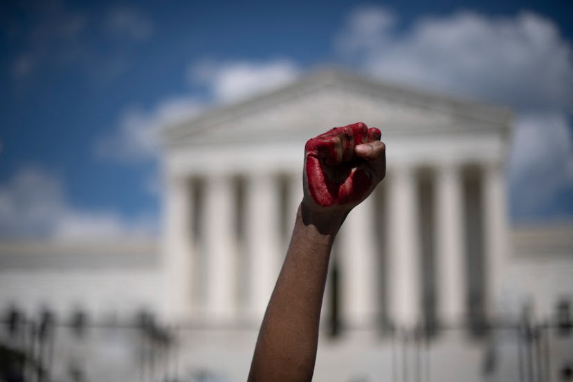 An abortion rights demonstrator raises their fist, painted in red, in the air while yelling during a...