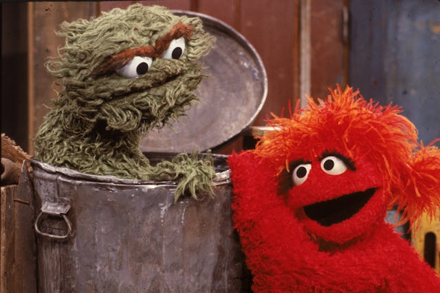 A red muppet visits Oscar the Grouch, inside his garbage can, in a scene from the children's televis...