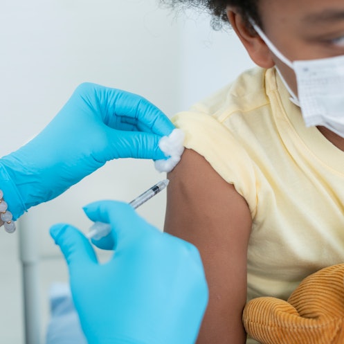 Close up of a doctor giving a child under 5 the COVID vaccine.