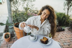 Smiling woman with long hair drinking tea and eating cake outdoors. Here's your june 28 zodiac sign ...