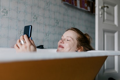 A woman sending a morning dirty text to her boyfriend in the bath. 