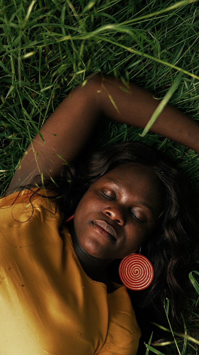 Woman lying in the grass with her eyes closed. Neptune retrograde 2022 is in its home sign, Pisces.