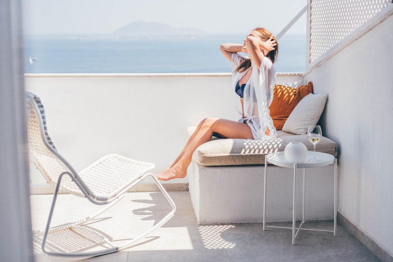 Woman in swimsuit relaxing on the balcony.  Woman sitting on a hotel balcony with sea view.