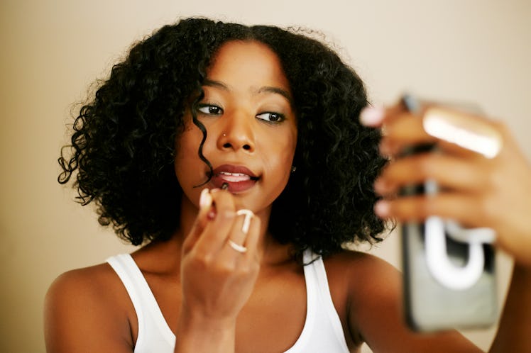 Woman putting on makeup to send a dirty text to her boyfriend. 