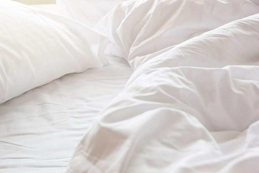 bed with rumpled sheets in an article about how to wash a mattress cover