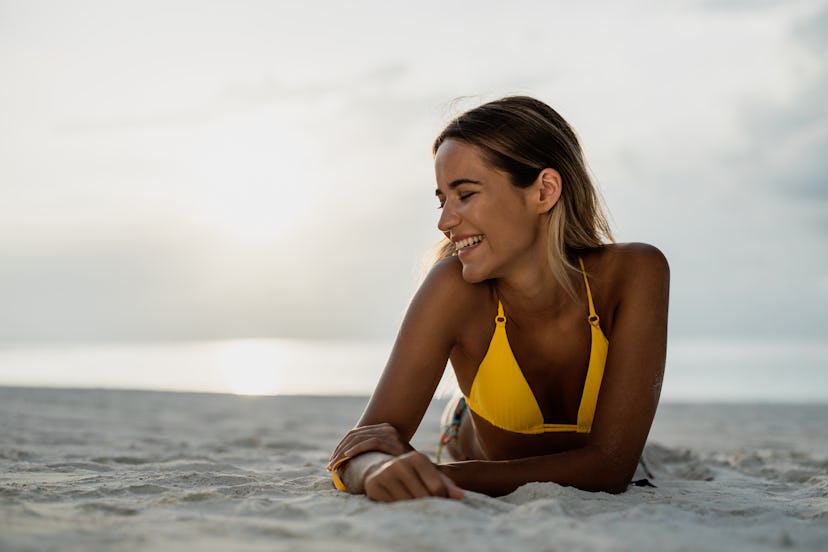 Young happy woman enjoying while relaxing in sand on the beach. Copy space.