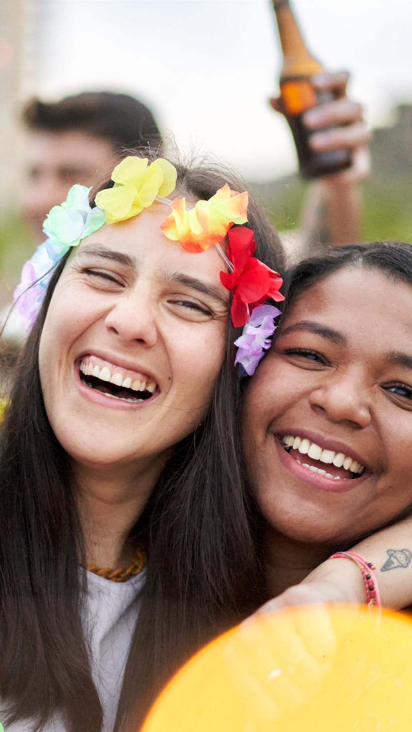 Happy close up photo of three friends laughing and having fun in a beach festival, embracing each ot...