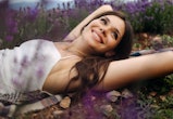 Smiling young woman lying in lavender. Aries, Gemini, Cancer, and Sagittarius zodiac signs will have...